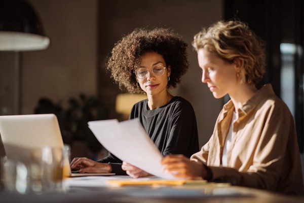 Two research professionals collaborating on project documents, representing MindMarket's dedicated project manager approach to global qualitative research
